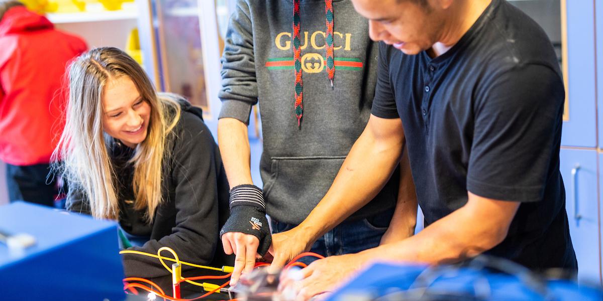 To elever og en lærer foetager et forsøg i fysiklokalet